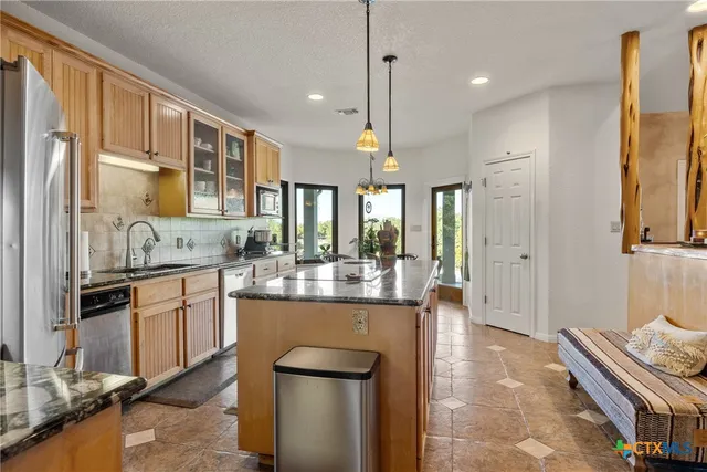 a kitchen with stainless steel appliances granite countertop a refrigerator a sink dishwasher a stove and white cabinets with wooden floor