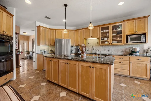 a kitchen with stainless steel appliances granite countertop a stove a sink and a refrigerator