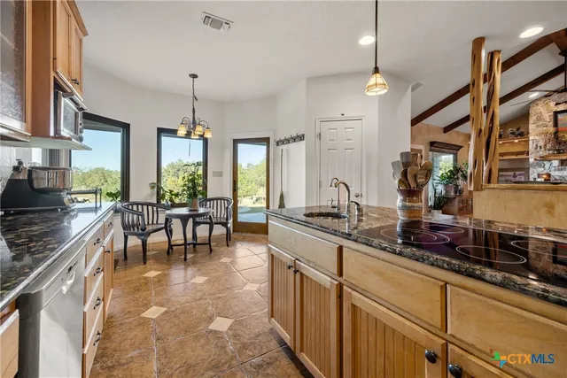 a kitchen with stainless steel appliances granite countertop table chairs and a stove