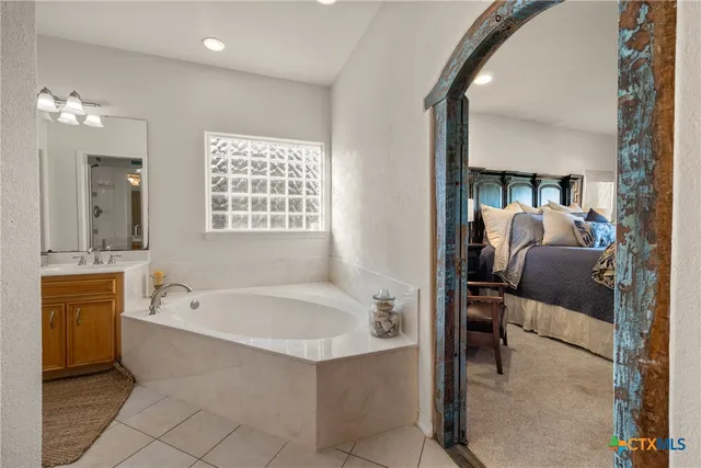 a en suite spacious bathroom with a tub double vanity and mirror