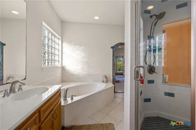 a bathroom with a granite countertop sink a mirror a bathtub and shower