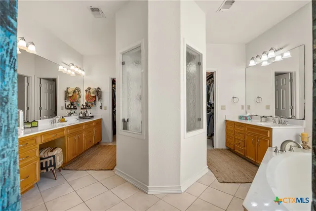 a large en suite bathroom with a tub double vanity sink and mirror