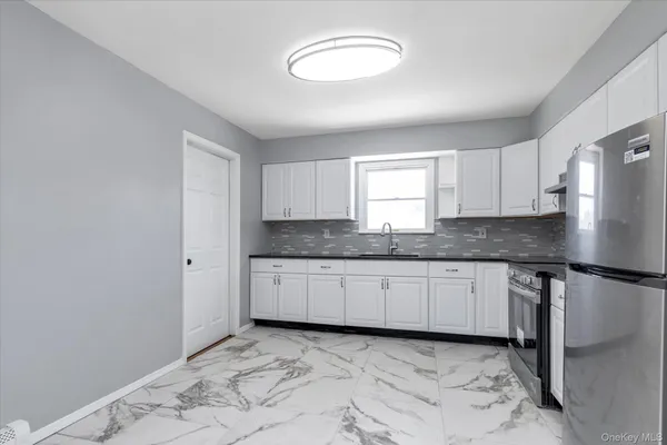 a kitchen with granite countertop a sink a stove a refrigerator and cabinets