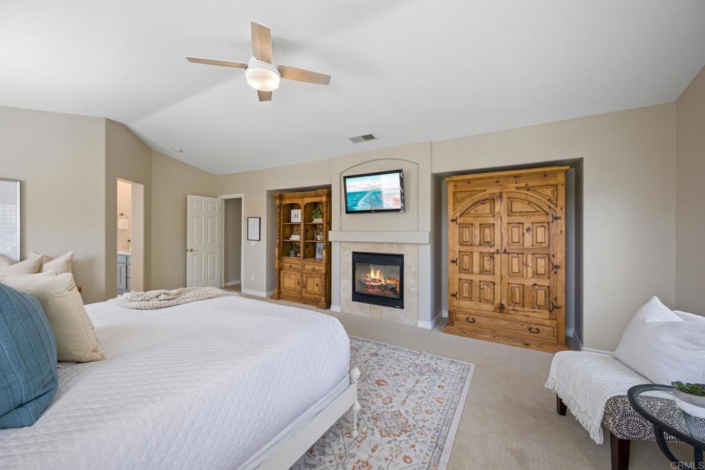 2107 Sun Valley Road San Marcos, CA 92078 - Photo 24 of 41 a spacious bedroom with a bed a fireplace and a chandelier