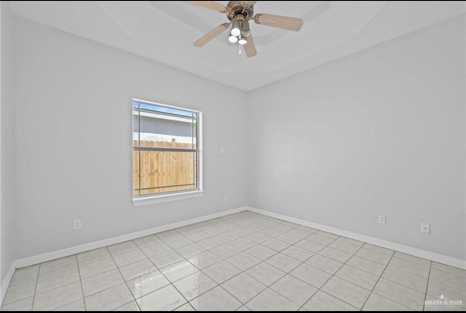 1900 Magnolia Street Mission, TX 78573 - Photo 14 of 25 Spare room featuring a ceiling fan, a tray ceiling, and light tile patterned flooring