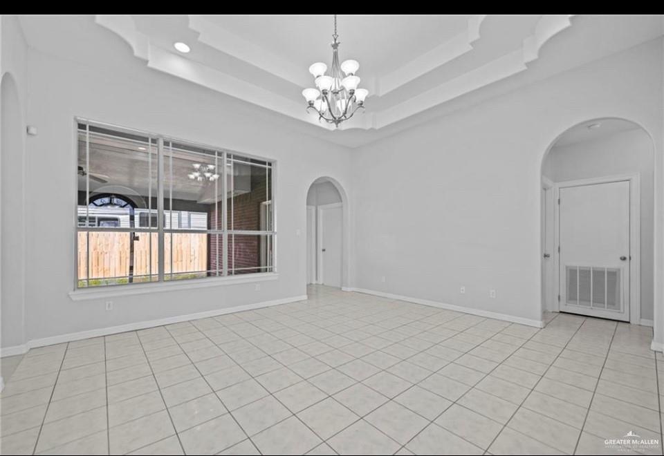 1900 Magnolia Street Mission, TX 78573 - Photo 10 of 25 Spare room featuring arched walkways, a tray ceiling, and a chandelier