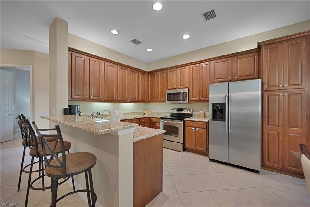 6522 Monterey Point, Unit 101 Naples, FL 34105 - Photo 5 of 29 a kitchen with stainless steel appliances granite countertop a refrigerator and a stove top oven