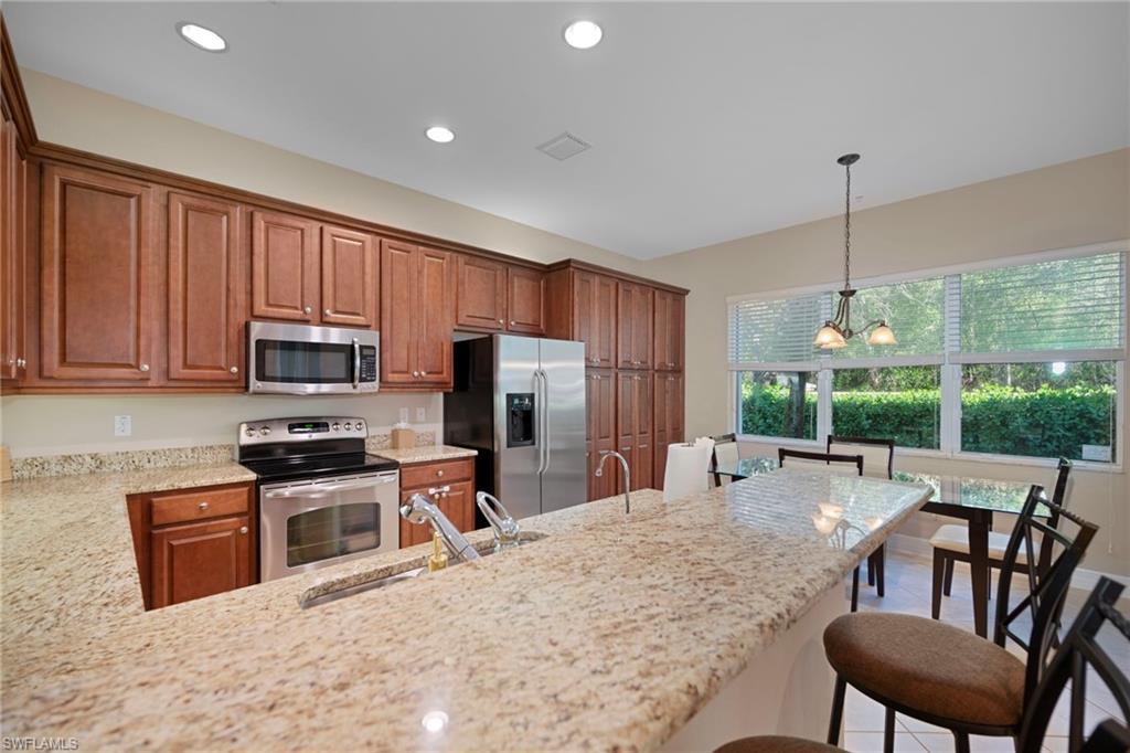 6522 Monterey Point, Unit 101 Naples, FL 34105 - Photo 6 of 29 a kitchen with stainless steel appliances granite countertop a stove top oven a sink refrigerator and cabinets