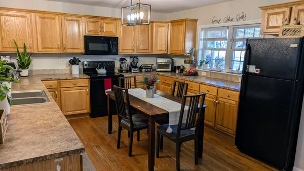 a kitchen with stainless steel appliances granite countertop a refrigerator a stove top oven a sink dishwasher and wooden cabinets