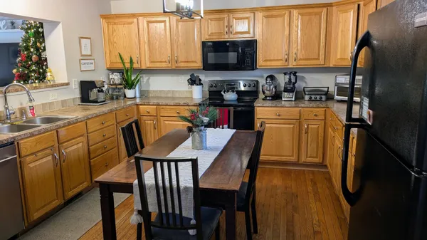 a kitchen with stainless steel appliances granite countertop a table chairs microwave and sink