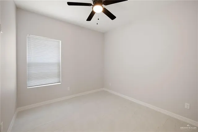 an empty room with a window and a ceiling fan