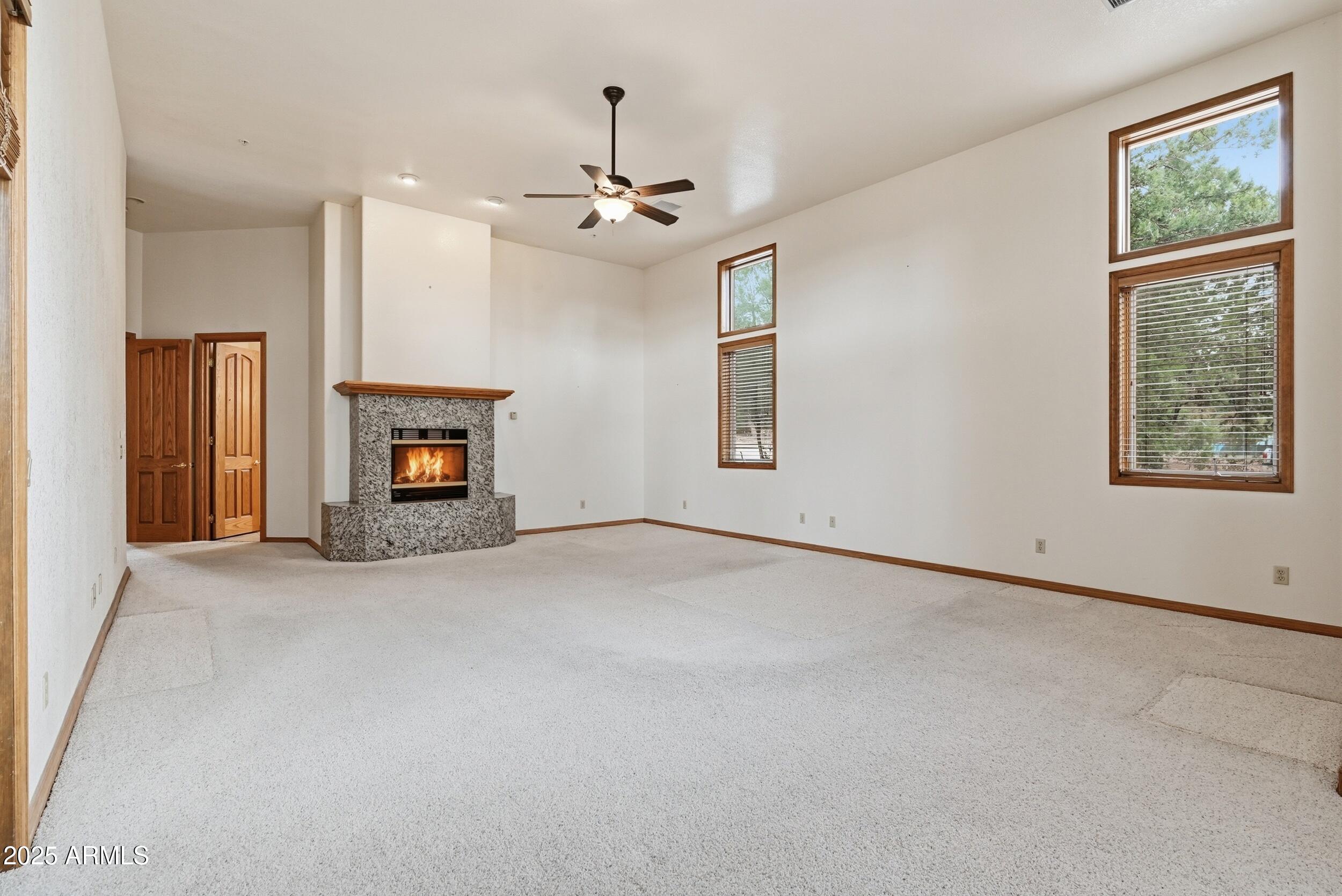 1606 Becky Circle Payson, AZ 85541 - Photo 33 of 58 an empty room with windows fireplace and a chandelier fan