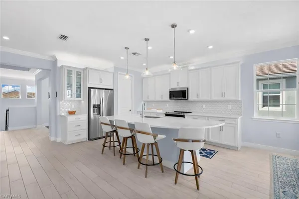 a kitchen with stainless steel appliances kitchen island granite countertop a dining table chairs stove refrigerator and cabinets