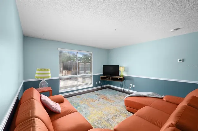 a living room with furniture a flat screen tv and a window