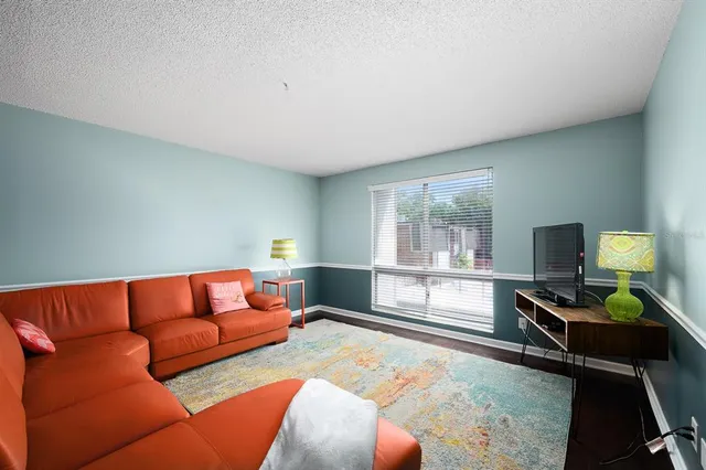 a living room with furniture a flat screen tv and a large window