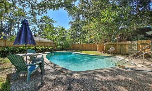 a view of a backyard with table and chairs potted plants and large tree