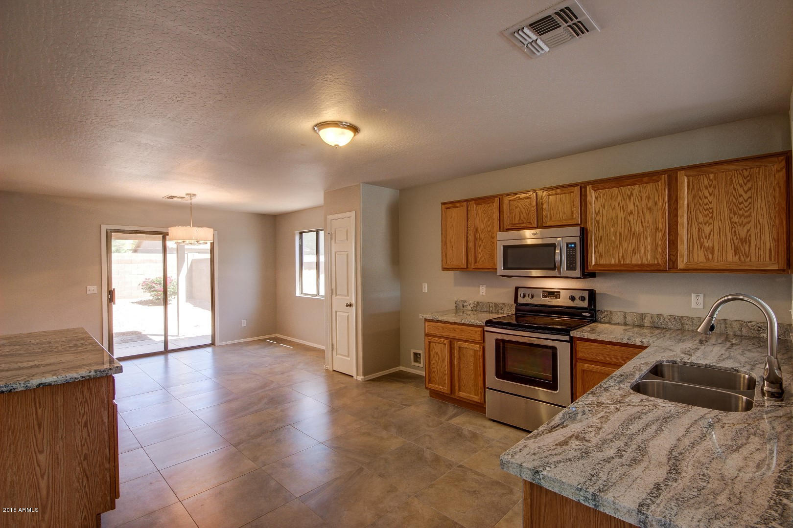 16148 West Boca Raton Road Surprise, AZ 85379 - Photo 3 of 24 a kitchen with stainless steel appliances granite countertop a stove a sink a refrigerator white cabinets and wooden floor