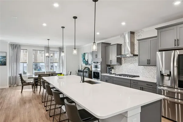 a kitchen with stainless steel appliances a dining table chairs refrigerator and sink