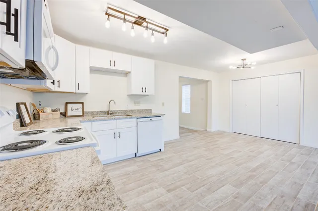 a kitchen with granite countertop a sink stove and cabinets