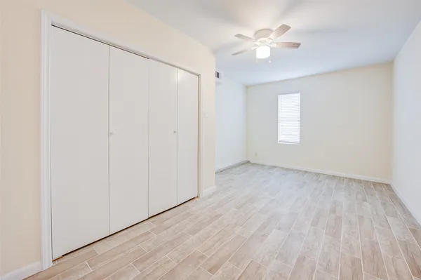 a view of an empty room with a window and a ceiling fan