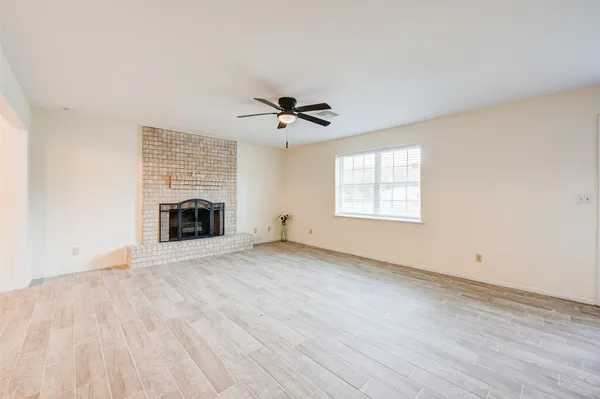 an empty room with chandelier fan and windows