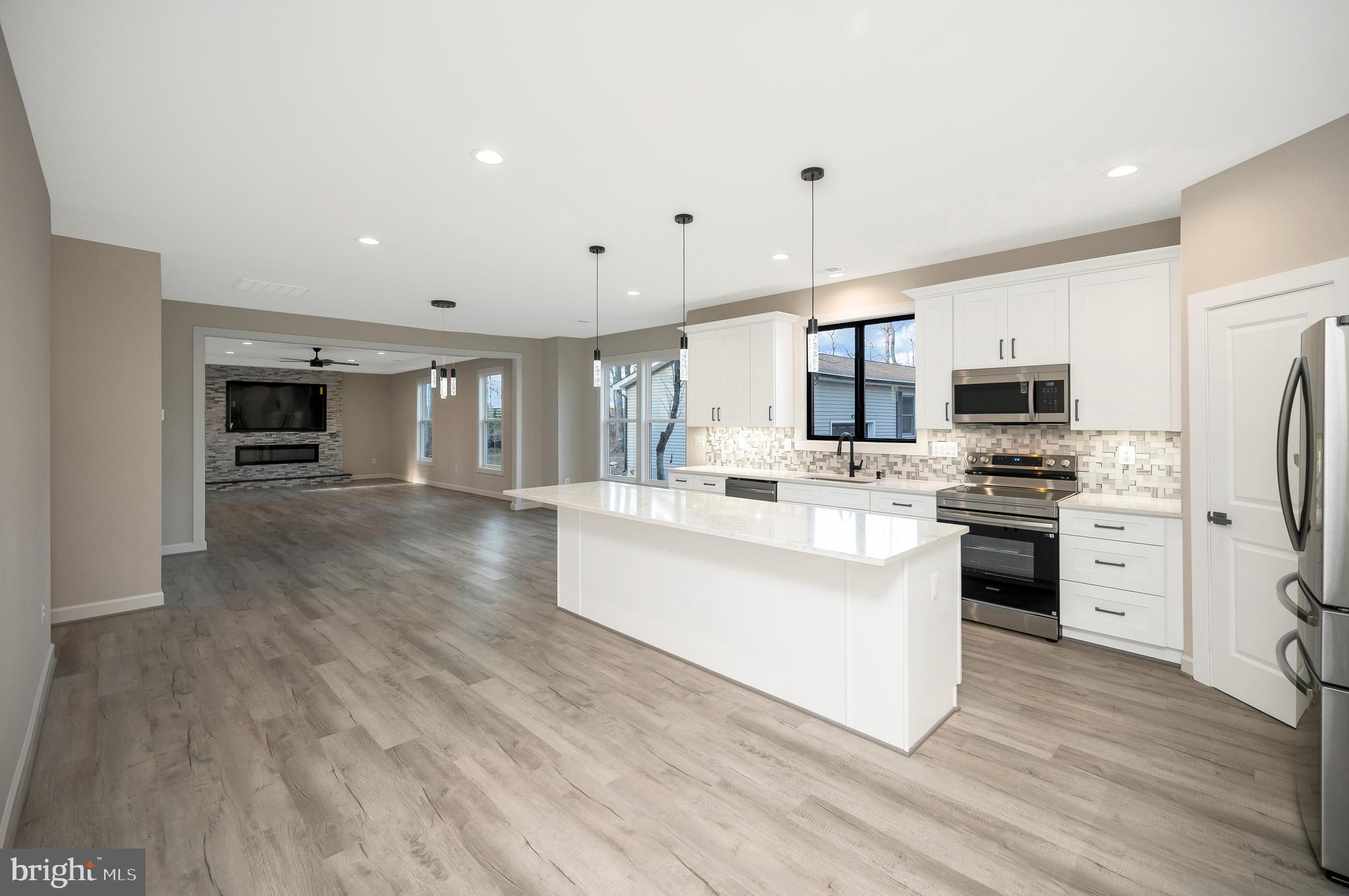 430 Liberty Boulevard Locust Grove, VA 22508 - Photo 15 of 66 a large white kitchen with stainless steel appliances kitchen island granite countertop a stove a sink a refrigerator and white cabinets with wooden floor