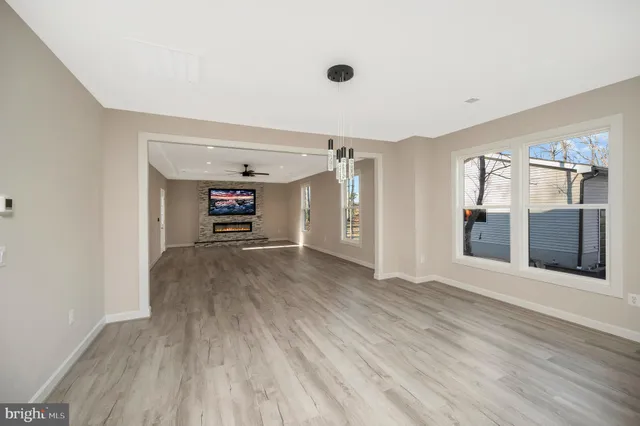 an empty room with wooden floor ceiling fan and windows