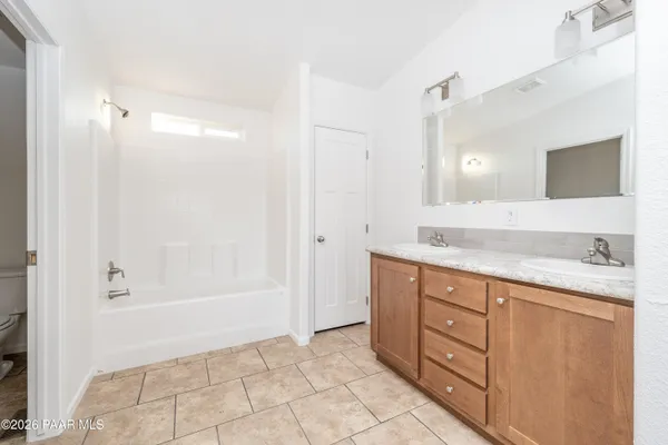 a bathroom with a granite countertop sink a mirror and a bathtub