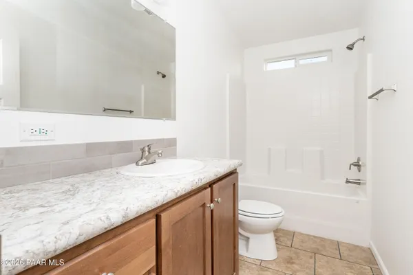 a bathroom with a granite countertop sink toilet a large mirror a bathtub and shower
