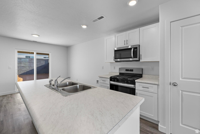 1597 South Fins Road, Unit 4177 Washington, UT 84780 - Photo 7 of 33 Bright kitchen featuring white cabinetry, a stainless steel microwave and range, and an island with a double basin sink