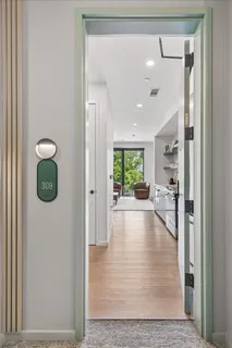 a view of a hallway with wooden floor and living room