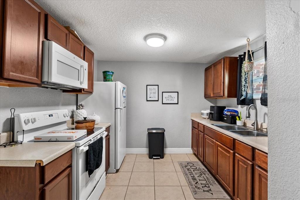 812 West Bryan Street Kissimmee, FL 34741 - Photo 11 of 27 a kitchen with stainless steel appliances granite countertop a stove a sink dishwasher and a refrigerator with wooden cabinets