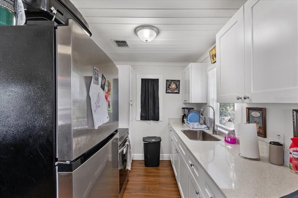 812 West Bryan Street Kissimmee, FL 34741 - Photo 23 of 27 a kitchen with stainless steel appliances a sink dishwasher a refrigerator and white cabinets with wooden floor