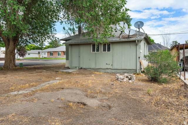 370 West 800 South Beaver, UT 84713 - Photo 13 of 15 Rear exterior of a single-story residence featuring light green vertical siding and a dark shingle roof