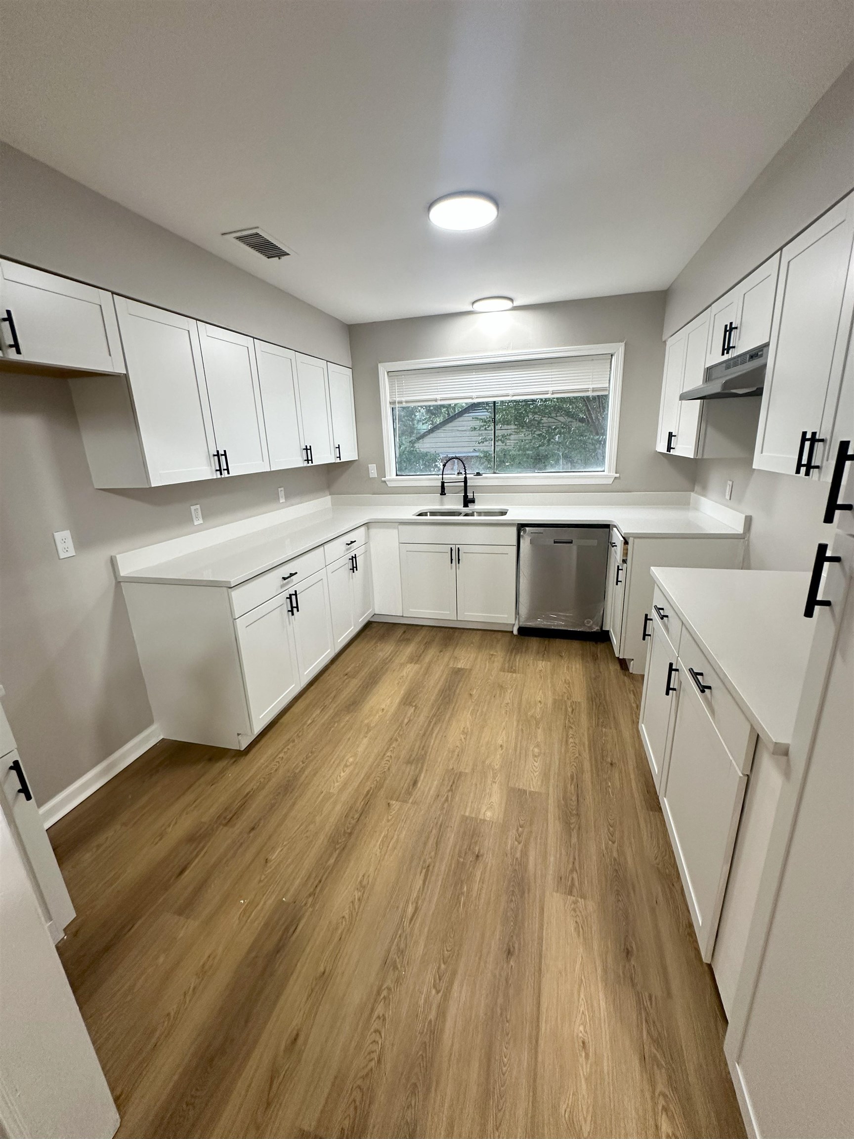 2820 Range Line Road Memphis, TN 38127 - Photo 7 of 35 a large kitchen with a white stove top oven a sink dishwasher and white cabinets with wooden floor