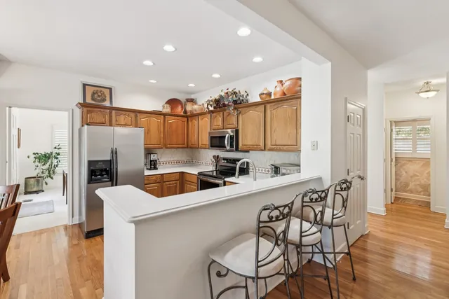 a kitchen with stainless steel appliances a sink dishwasher a microwave oven and a dining table with wooden floor