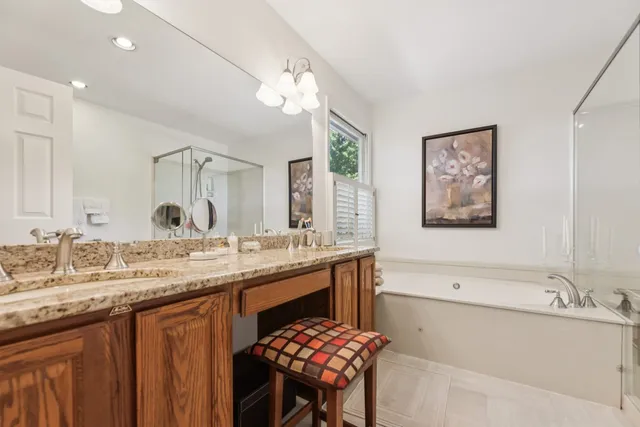 a bathroom with a granite countertop sink a large mirror and a bathtub