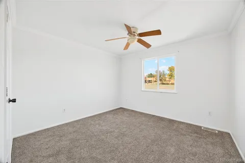 an empty room with ceiling fan and window