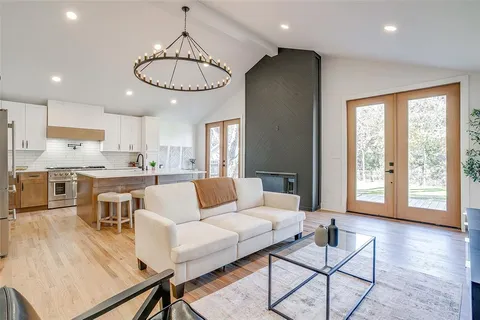 a living room kitchen with a dining table wooden floor and kitchen view