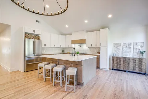 a kitchen with stainless steel appliances granite countertop a stove top oven a sink dishwasher a dining table and chairs with wooden floor