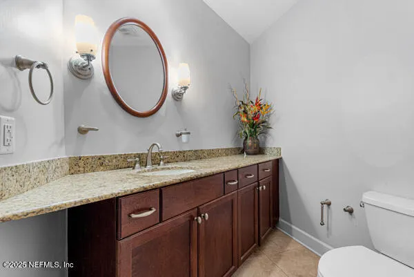 a bathroom with a granite countertop toilet sink and mirror