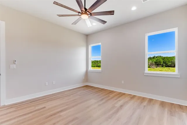 an empty room with a window and a ceiling fan