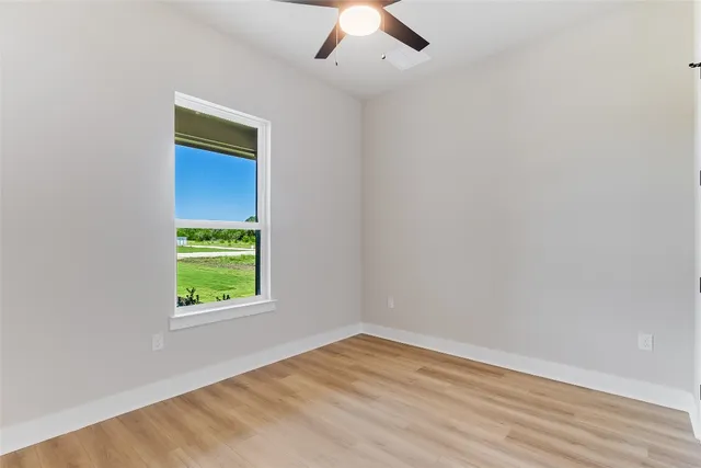 an empty room with a window and a ceiling fan