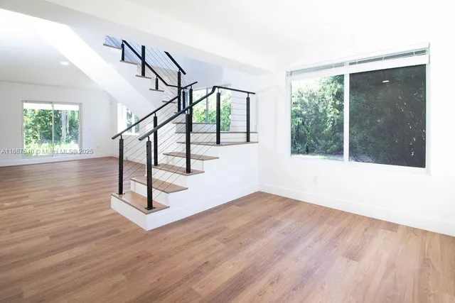 a view of a big room with wooden floor and windows