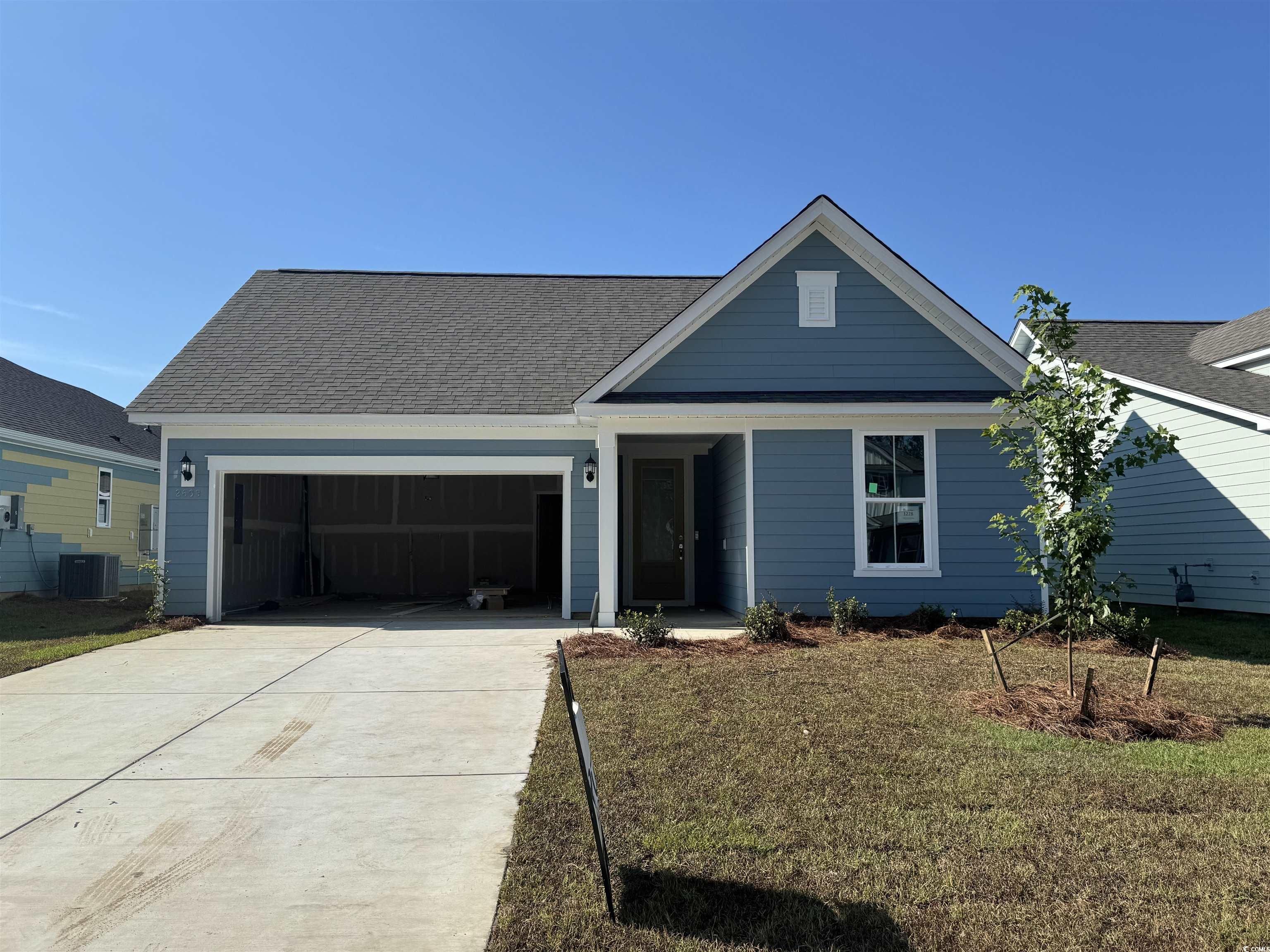 View of front of home with a front yard, a garage, driveway, and a shingled roof