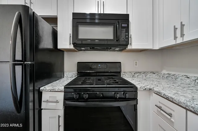 a kitchen with stainless steel appliances granite countertop a stove microwave and refrigerator