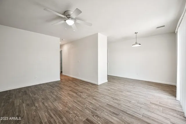 an empty room with wooden floor and ceiling fan