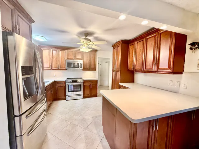 a kitchen with stainless steel appliances kitchen island granite countertop a refrigerator a stove and a sink