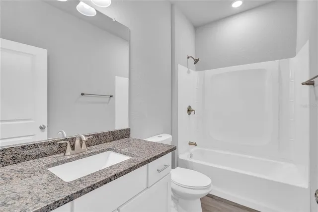 a bathroom with a granite countertop sink a toilet and bathtub