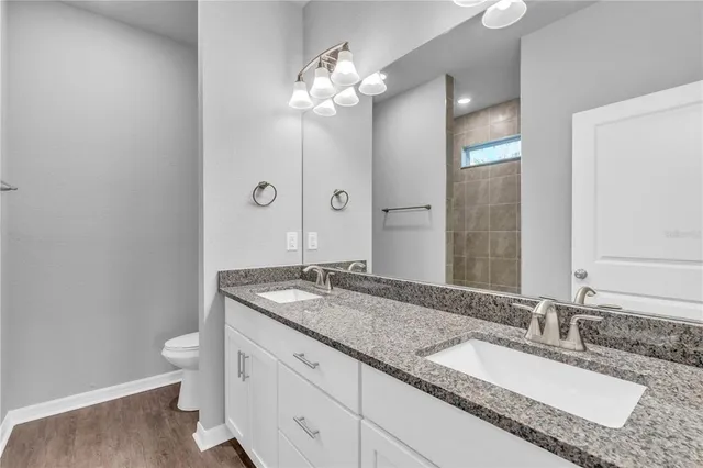 a bathroom with a granite countertop double vanity sink and a mirror